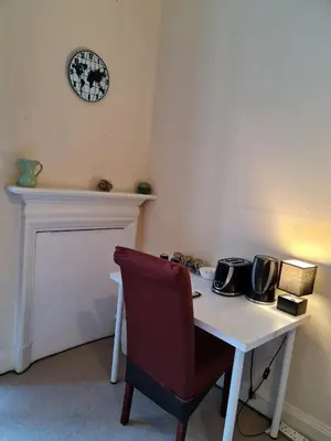 a white table with a chair and a clock on the wall at Haymarket Station Rooms in Edinburgh