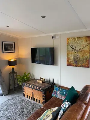 a living room with a couch and a flat screen tv at Lovely new caravan by Loch Long in Cove