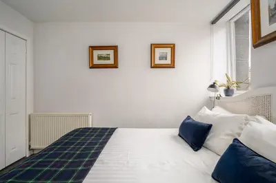 a white bed with blue pillows in a bedroom at The Riverside Hideaway by Calton Living in Edinburgh