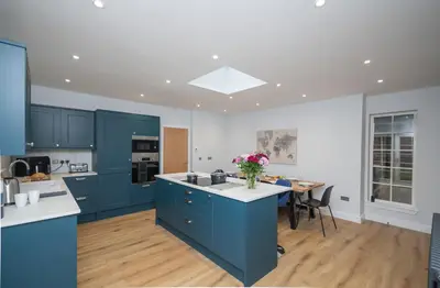 a kitchen with blue cabinets and a table with a vase of flowers at Historical Holmehill Lodge in Dunblane