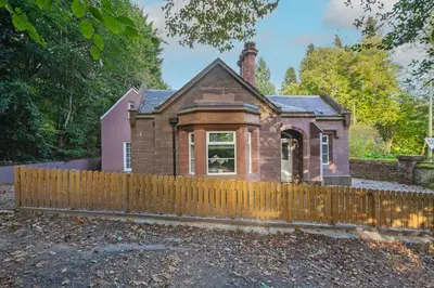 an old brick house with a wooden fence at Historical Holmehill Lodge in Dunblane
