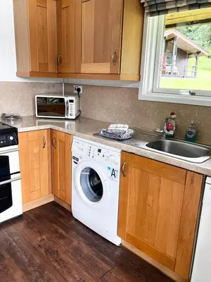 a kitchen with a washing machine and a sink at Stringy Rocks in Morenish