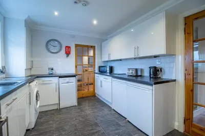 a kitchen with white appliances and a clock on the wall at The Brigg in Coatbridge