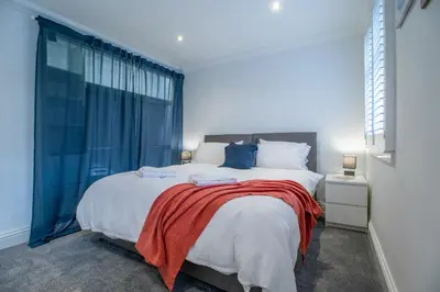 a bedroom with a large bed with a red blanket on it at The Brigg in Coatbridge