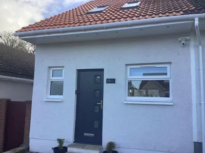 a white house with a black door and a red roof at The Annexe in Eaglesham