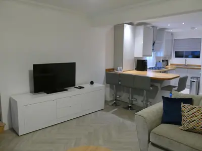 a living room with a flat screen tv on a white cabinet at The Annexe in Eaglesham