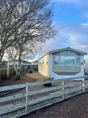 a yellow and white house with a fence at Red Deer Village Holiday Park - 3 Bedroom, Self-Catering Holiday Home in Steps