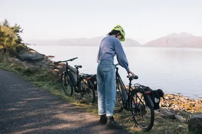 a man standing next to two bikes next to a lake at Forest Corner Luxury Home with Hot Tub in North Ballachulish