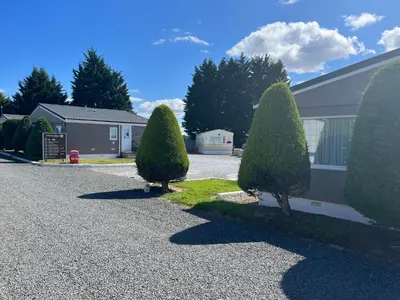 a driveway with three trees in front of a house at Red Deer Village Holiday Park - 3 Bedroom, Self-Catering Chalet in Steps