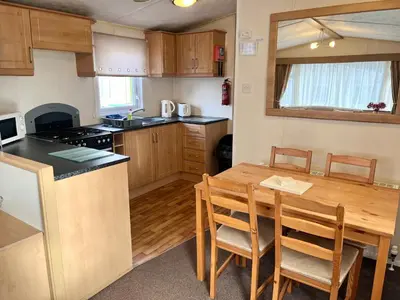 a kitchen with a wooden table and a dining room at Red Deer Village Holiday Park - 3 Bedroom, Self Catering Static Caravan in Steps