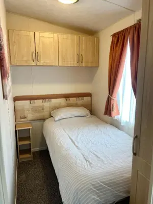 a small bedroom with a bed and a window at Red Deer Village Holiday Park - 3 Bedroom, Self Catering Static Caravan in Steps