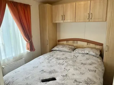 a bedroom with a bed with a remote control on it at Red Deer Village Holiday Park - 3 Bedroom, Self Catering Static Caravan in Steps