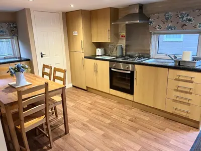a kitchen with a wooden table and a wooden floor at Red Deer Village Holiday Park - 2 Bedroom, Self-Catering Chalet in Steps