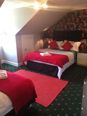 a bedroom with two beds with red sheets and red pillows at Broom Lodge in Largs