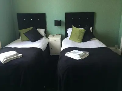 two beds in a hotel room with towels on them at Broom Lodge in Largs