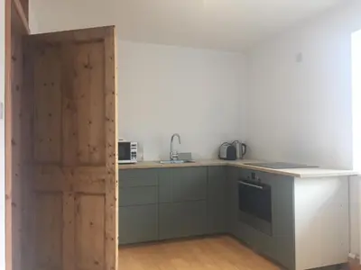a kitchen with a counter with a sink and a door at Willow Cottage, Gilchristland Organic Farm in Closeburn