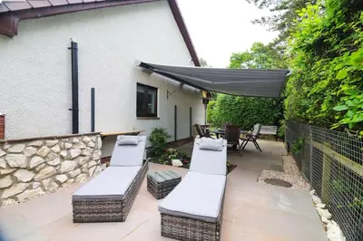a patio with four lounge chairs and an umbrella at Woodhead view in Kirkintilloch