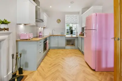 a pink refrigerator in a kitchen with a wooden floor at Seaside Place, Aberdour in Aberdour