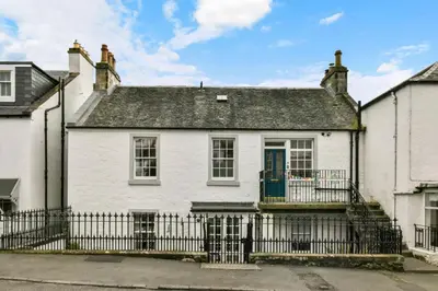 a white house with a black fence at Seaside Place, Aberdour in Aberdour