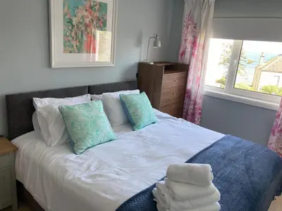 a bedroom with a white bed with pillows and a window at Blacksands Seaview Cottage, Aberdour in Aberdour