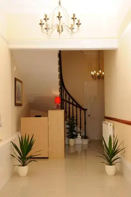 a hallway with a staircase with plants and a chandelier at Edinburgh City Suites in Edinburgh