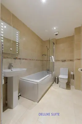 a bathroom with a tub and a sink and a toilet at Edinburgh City Suites in Edinburgh