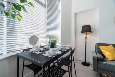 a dining room table with chairs and a window with blinds at Dyke Apartment in Bailleston