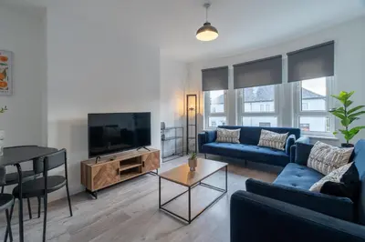 a living room with a blue couch and a tv at Locksley House in Knightswood