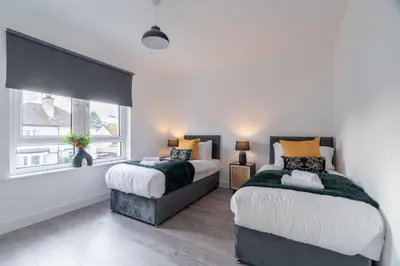 a bedroom with two beds and a window at Locksley House in Knightswood