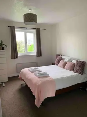 a bedroom with a large bed with a pink blanket on it at Facing Glasgow Green spacious Apartment Free parking in Glasgow