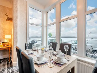 a dining room with a table with chairs and windows at Argyle House in Rothesay