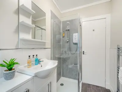 a white bathroom with a sink and a shower at Argyle House in Rothesay