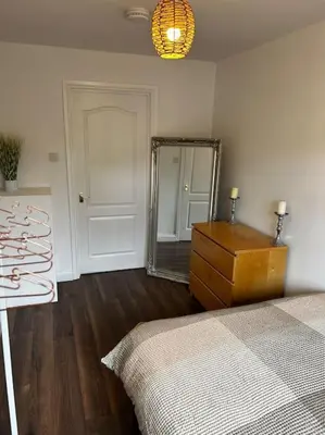 a bedroom with a bed and a dresser and a mirror at 15 min drive to airport 20 min to Loch Lomond and city center in Old Kilpatrick
