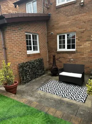 a patio with a couch and a chair in front of a brick building at 15 min drive to airport 20 min to Loch Lomond and city center in Old Kilpatrick