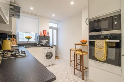a kitchen with a stove top oven and a washer and dryer at Henry Bell - Cosy 2-bedroom cottage in Helensburgh