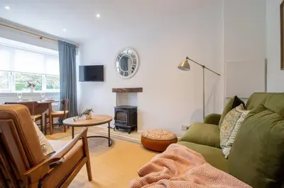 a living room with a green couch and a table at Henry Bell - Cosy 2-bedroom cottage in Helensburgh