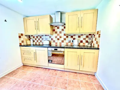 a kitchen with wooden cabinets and a tiled wall at Luxury Smugglers Cottage in the Heart of Inveraray Sleeps 4 in 2 Bedrooms in Inveraray