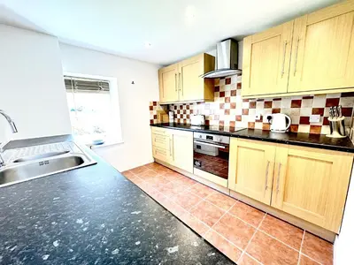 a kitchen with wooden cabinets and black counter tops at Luxury Smugglers Cottage in the Heart of Inveraray Sleeps 4 in 2 Bedrooms in Inveraray