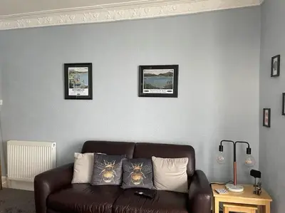 a couch in a living room with three pictures on the wall at Bellevue Bute, Luxury 2 bedroom sea view flat in Rothesay