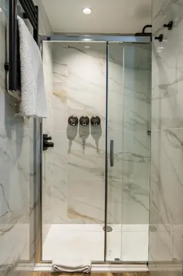 a glass shower in a bathroom with two glasses at Tynecastle Park Hotel in Edinburgh