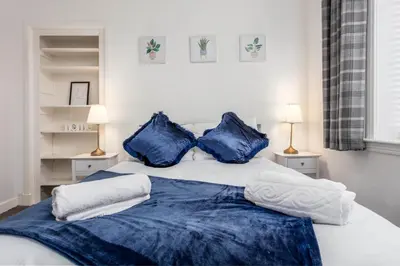 a bedroom with a bed with blue pillows at Berelands House - Donnini Apartments in Prestwick