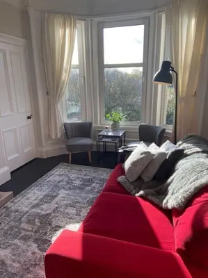 a red couch in a living room with a window at Beautiful traditional top floor flat in the center of Largs in Largs