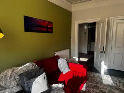 a living room with a red couch and a green wall at Beautiful traditional top floor flat in the center of Largs in Largs