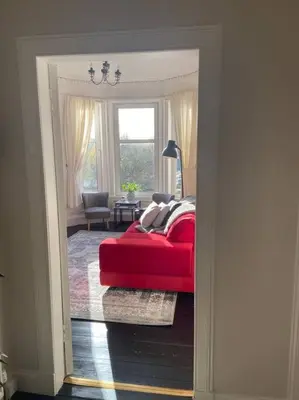 a red couch in a living room with a window at Beautiful traditional top floor flat in the center of Largs in Largs
