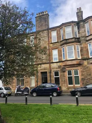 a large brick building with cars parked in front of it at Beautiful traditional top floor flat in the center of Largs in Largs