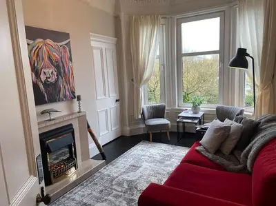 a living room with a red couch and a fireplace at Beautiful traditional top floor flat in the center of Largs in Largs