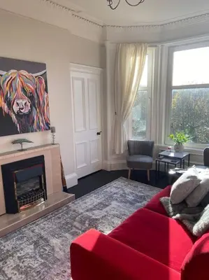 a living room with a red couch and a fireplace at Beautiful traditional top floor flat in the center of Largs in Largs