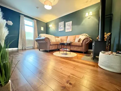 a living room with a couch and a table at Chestnut Cottage in Dalmellington