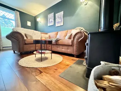 a living room with a couch and a table at Chestnut Cottage in Dalmellington