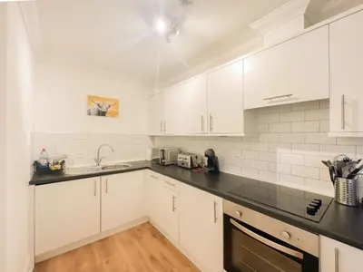 a kitchen with white cabinets and black counter tops at Cozy 1 bed Blythswood Apartment in Glasgow